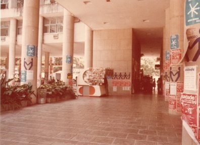 Na entrada da Ala Frings, paredes cobertas com propagandas do movimento estudantil na PUC-Rio. Ao centro a banca de jornal que ficava onde atualmente há um caixa eletrônico. 1985. Fotógrafo desconhecido. Acervo do Projeto Comunicar.