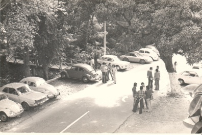 Vista da via de passagem principal da PUC-Rio e da primeira ponte de acesso ao Edifício da Amizade, com alunos e carros. 1980. Fotógrafo Antônio Albuquerque. Acervo da Vice-Reitoria de Desenvolvimento.