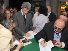 À direita, o prof. Hilton Koch escreve dedicatória no livro durante o evento. Fotógrafo Antônio Albuquerque. Acervo do Núcleo de Memória.