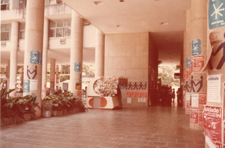 Na entrada da Ala Frings, paredes cobertas com propagandas do movimento estudantil na PUC-Rio. Ao centro a banca de jornal que ficava onde atualmente há um caixa eletrônico. 1985. Fotógrafo desconhecido. Acervo do Projeto Comunicar.