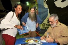 Na foto o Prof. Adair Rocha autografa um livro. Ao seu lado direito está o escritor Nélson Rodrigues Filho. Fotógrafo Weiler Filho. Acervo do Núcleo de Memória.
