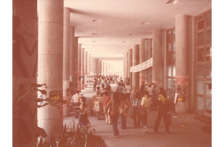 Movimento nos pilotis do Edifício Cardeal Leme com faixas e cartazes de eleições estudantis. c. 1980. Fotógrafo desconhecido. Acervo Núcleo de Memória.