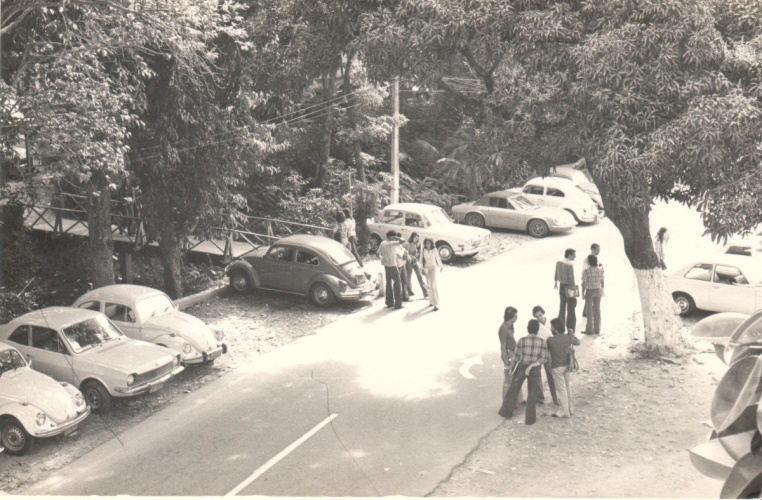 Vista da via de passagem principal da PUC-Rio e da primeira ponte de acesso ao Edifício da Amizade, com alunos e carros. 1980. Fotógrafo Antônio Albuquerque. Acervo da Vice-Reitoria de Desenvolvimento.