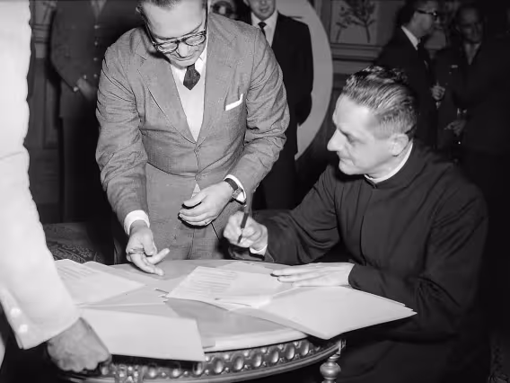 O prof. Del Castilho (EPUC) e o então Vice-reitor pe. Laércio S.J. na assinatura do convênio. Fotógrafo Manuel Marques Mesquita. Arquivo Nacional/Agência Nacional.