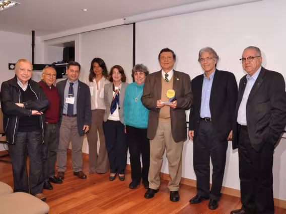 Na foto, com o troféu comemorativo dos 21 anos do PIUES, o Prof. Scavarda, e alguns dos presentes, como o Reitor Prof. Pe. Josafá S.J. Fotógrafa Gabriela Doria. Acervo do Projeto Comunicar.