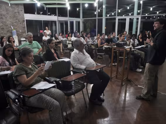 O prof. Joel Pizzini apresenta Aula Inaugural do Curso, em auditório do Centro Loyola de Fé e Cultura. Na audiência a profa. Angeluccia Habert (COM) e o Prof. Adair Rocha (COM). Fotógrafo Weiler Filho. Acervo do Projeto Comunicar.