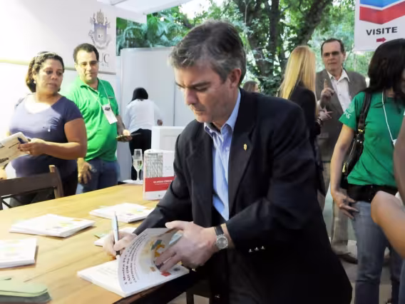 O Prof. André Lacombe autografa um dos livros durante o lançamento na Mostra PUC. Fotógrafa Pamella Vasconcellos. Acervo do Projeto Comunicar.