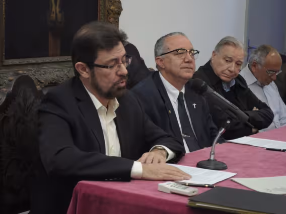 Mesa na sala do Conselho Universitário composta pelo Prof. Silva Mello, pelo Reitor Prof. Pe. Josafá Carlos de Siqueira S.J., pelo Prof. Pe. Ivern Simó S.J. e pelo Prof. Augusto Sampaio. Fotógrafo Antônio Albuquerque. Acervo do Núcleo de Memória.