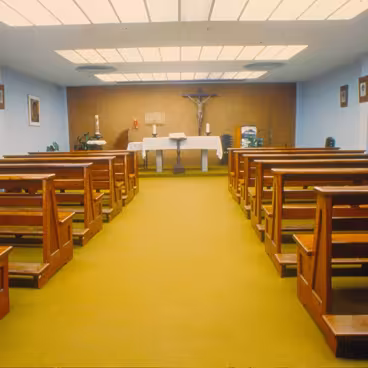 A antiga Capela, localizada no térreo do Edifício Cardeal Leme, onde se vê o crucifixo em madeira e a série de gravuras da via sacra, de Carlos Oswald, atualmente na Igreja do Sagrado Coração. 1984. Fotógrafo desconhecido. Acervo Núcleo de Memória da PUC-Rio.