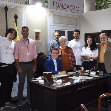 Visita do pe. Roberto Dias S.J. à Exposição Fundação - 40 anos, coma equipe do Núcleo de Memória da PUC-Rio. 2023. Fotógrafo Antônio Albuquerque. Acervo do Núcleo de Memória da PUC-Rio.